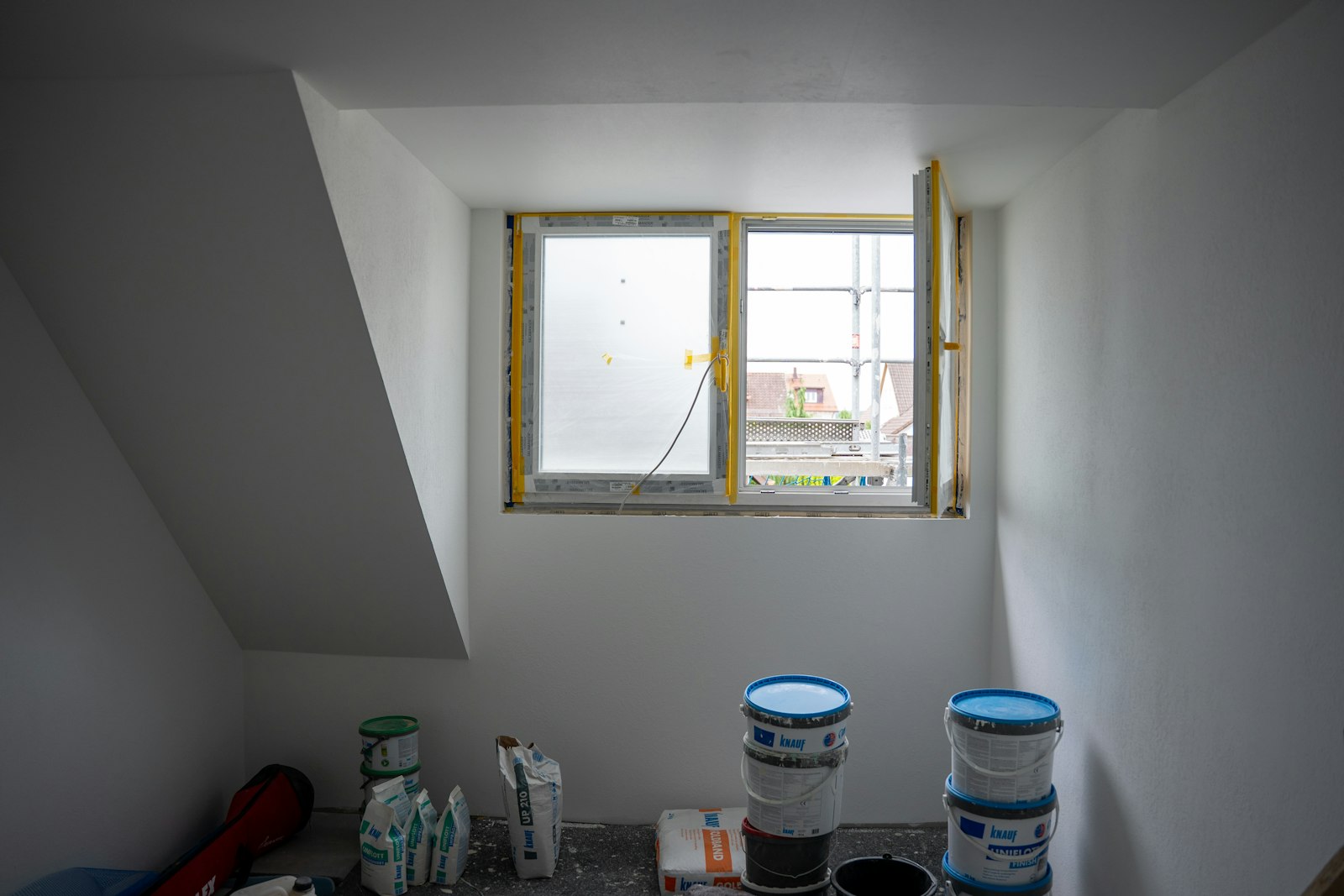 Room mid-preparation with taped windows and paint buckets